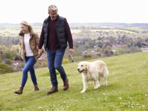 Middle aged couple walking dog in the grass